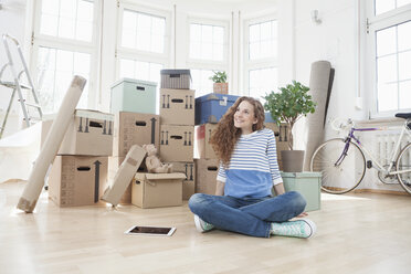 Woman surrounded by cardboard boxes sitting on floor - RBF004723