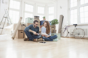 Couple surrounded by cardboard boxes sitting on floor - RBF004724