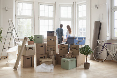 Ehepaar mit Kartons in neuer Wohnung schaut aus dem Fenster - RBF004734