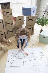Frau umgeben von Kartons mit Farbmustern und Bauplan auf dem Boden - RBF004737