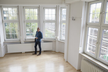 Man looking around in empty apartment - RBF004746