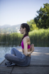 Young woman doing exercise on pier - MRAF000096