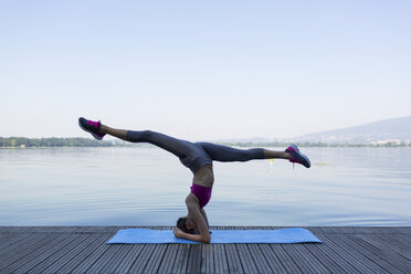 Young woman doing exercise on pier, headstand - MRAF000099
