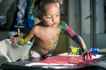 Mädchen malt rotes Bild mit Fingerfarben und ist völlig verschmiert von Farben - YNF000025
