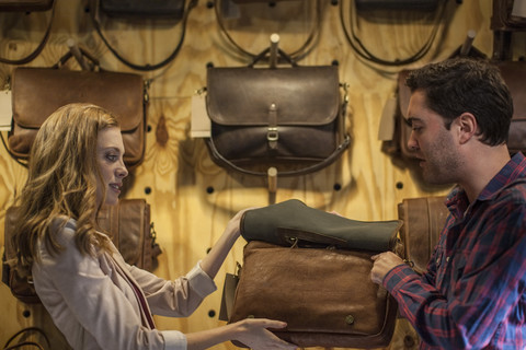 Mann und Frau betrachten eine Ledertasche in einem Geschäft, lizenzfreies Stockfoto