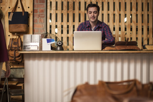 Mann mit Laptop auf dem Ladentisch - ZEF008936