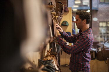 Man in shop exmining leather bags - ZEF008938