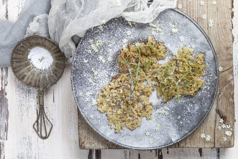 Baked elder flowers with icing sugar on plate - SBDF003016