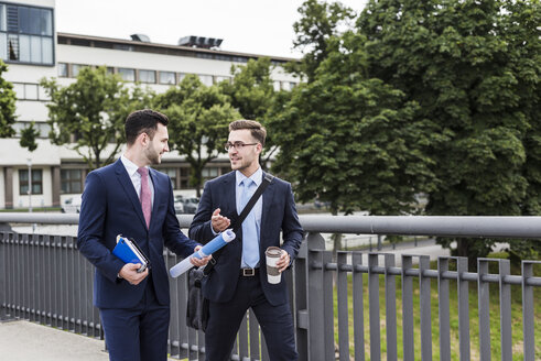 Zwei junge Geschäftsleute gehen zusammen durch die Stadt - UUF007977