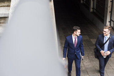 Two young businessmen walking together in the city - UUF007986