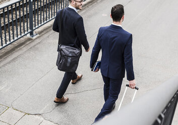Businessmen on business trip walking with wheeled luggage - UUF007987