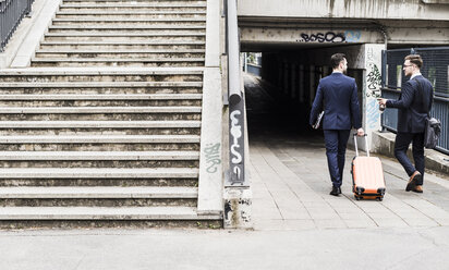 Businessmen on business trip walking with wheeled luggage - UUF007988