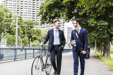 Geschäftsleute, die mit dem Fahrrad in der Stadt spazieren gehen und sich unterhalten - UUF008001