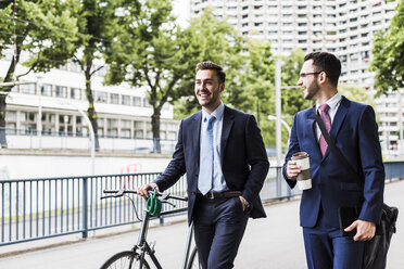 Geschäftsleute, die mit dem Fahrrad in der Stadt spazieren gehen und sich unterhalten - UUF008002