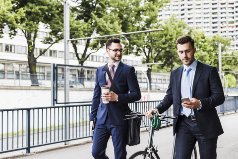 Geschäftsleute, die mit dem Fahrrad in der Stadt spazieren gehen und sich unterhalten, lizenzfreies Stockfoto