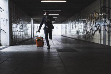 Businessman on business trip running with wheeled luggage - UUF008020