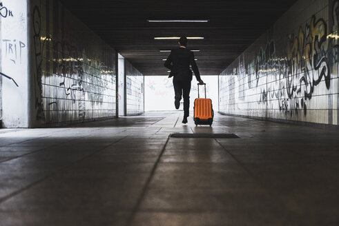 Geschäftsmann auf Geschäftsreise läuft mit Gepäck auf Rädern - UUF008021