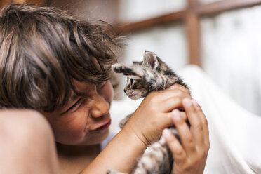 Little boy holding tabby kitten pulling funny face - VABF000666