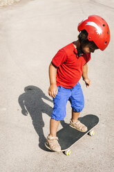 Kleiner Junge mit rotem Schutzhelm auf dem Skateboard stehend - VABF000668