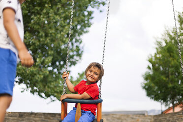 Porträt eines glücklichen kleinen Jungen, der auf einer Schaukel sitzt - VABF000670