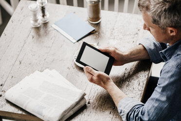 Älterer Mann sitzt im Café mit Zeitung und digitalem Tablet - KNSF000007