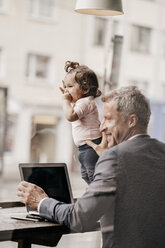 Businessman with little daughter working on laptop in cafe - KNSF000009