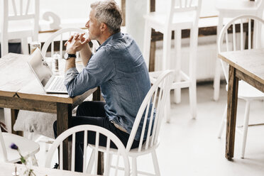 Älterer Mann sitzt im Café und benutzt einen Laptop - KNSF000027