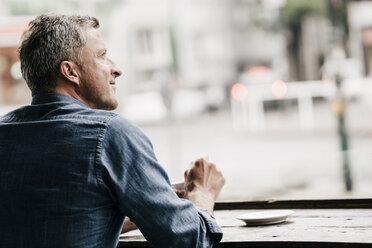 Mature man sitting in cafe looking out of window - KNSF000032