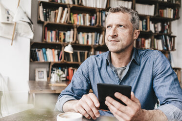 Mature man sitting in cafe reading e-book - KNSF000047