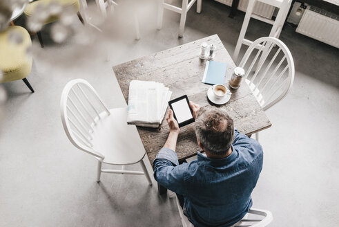 Älterer Mann sitzt im Café mit Zeitung und digitalem Tablet - KNSF000048