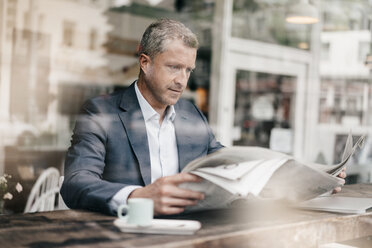 Businessman in cafe reading newspaper - KNSF000061