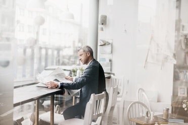 Businessman in cafe reading newspaper - KNSF000062