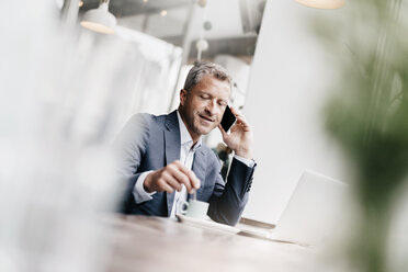 Businessman sitting in cafe, working - KNSF000064