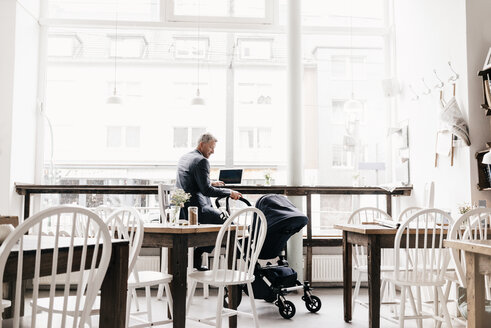 Geschäftsmann im Café sitzend mit Kinderwagen - KNSF000069