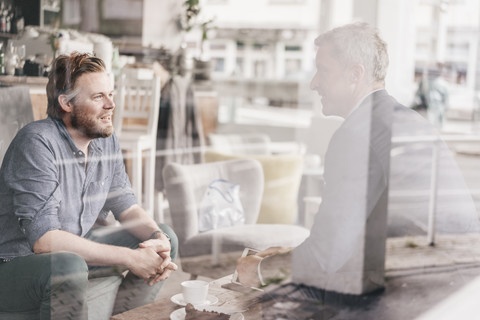 Geschäftsmann berät Kunden in einem Cafe, lizenzfreies Stockfoto