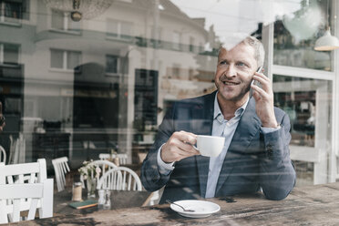 Businessman in cafe using smart phone - KNSF000091