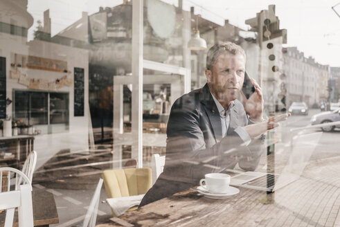 Geschäftsmann sitzt im Café und arbeitet - KNSF000092