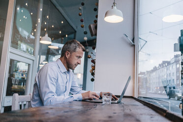 Businessman sitting in cafe, working - KNSF000098