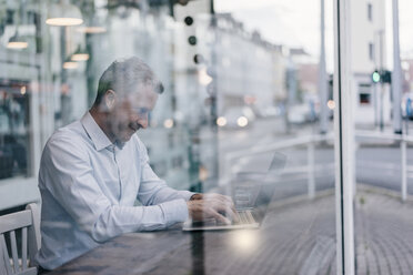 Businessman sitting in cafe, working - KNSF000100
