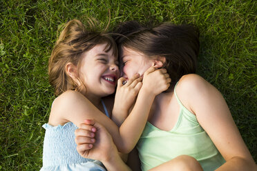 Two sisters lying in meadow having fun - LVF005112