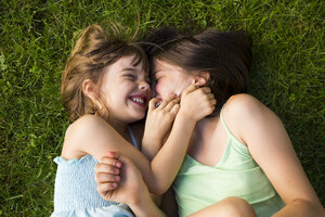 Two sisters lying in meadow having fun - LVF005112