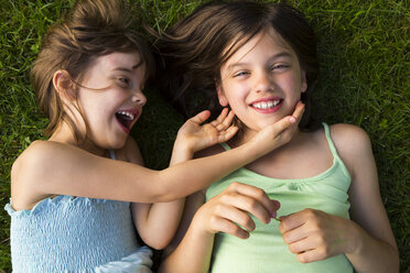 Two sisters lying in meadow having fun - LVF005113