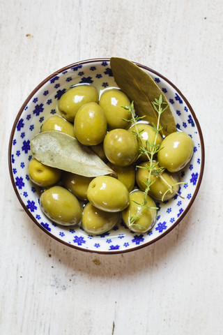 green olives in bowl with thyme and bay leaf stock photo