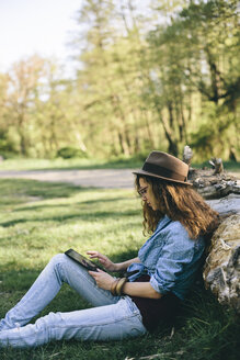 Woman sitting on a meadow using digital tablet - AKNF000047