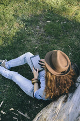 Woman sitting on a meadow using digital tablet - AKNF000051