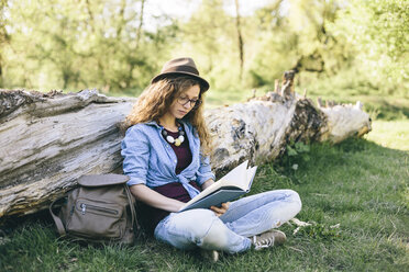 Woman sitting on a meadow reading a book - AKNF000055