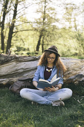 Woman sitting on a meadow reading a book - AKNF000057