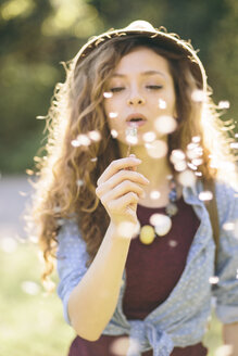 Young woman blowing dandelion - AKNF000058