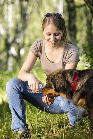 Junge Frau gibt ihrem Hund Wasser, lizenzfreies Stockfoto