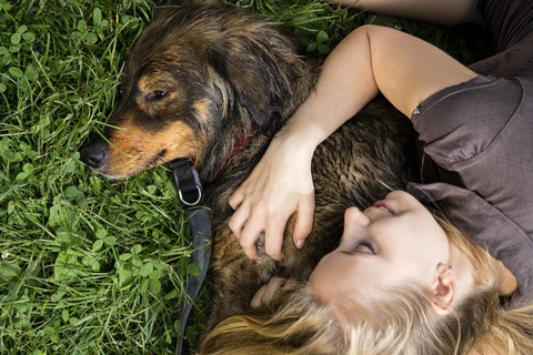 Young woman relaxing with her dog on a meadow stock photo